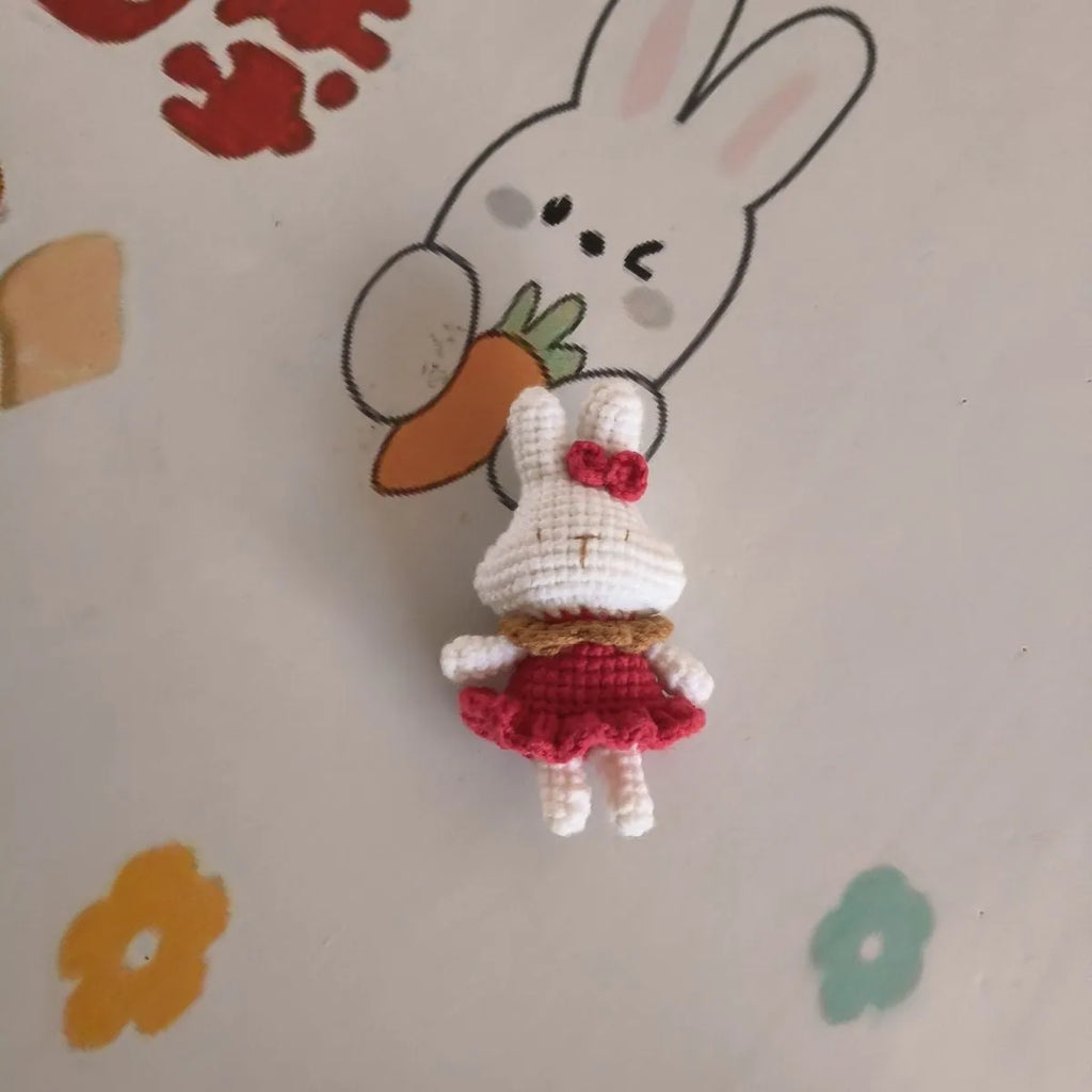 Hand-crocheted wool rabbit key chain pendant with key chain attachment on a soft surface