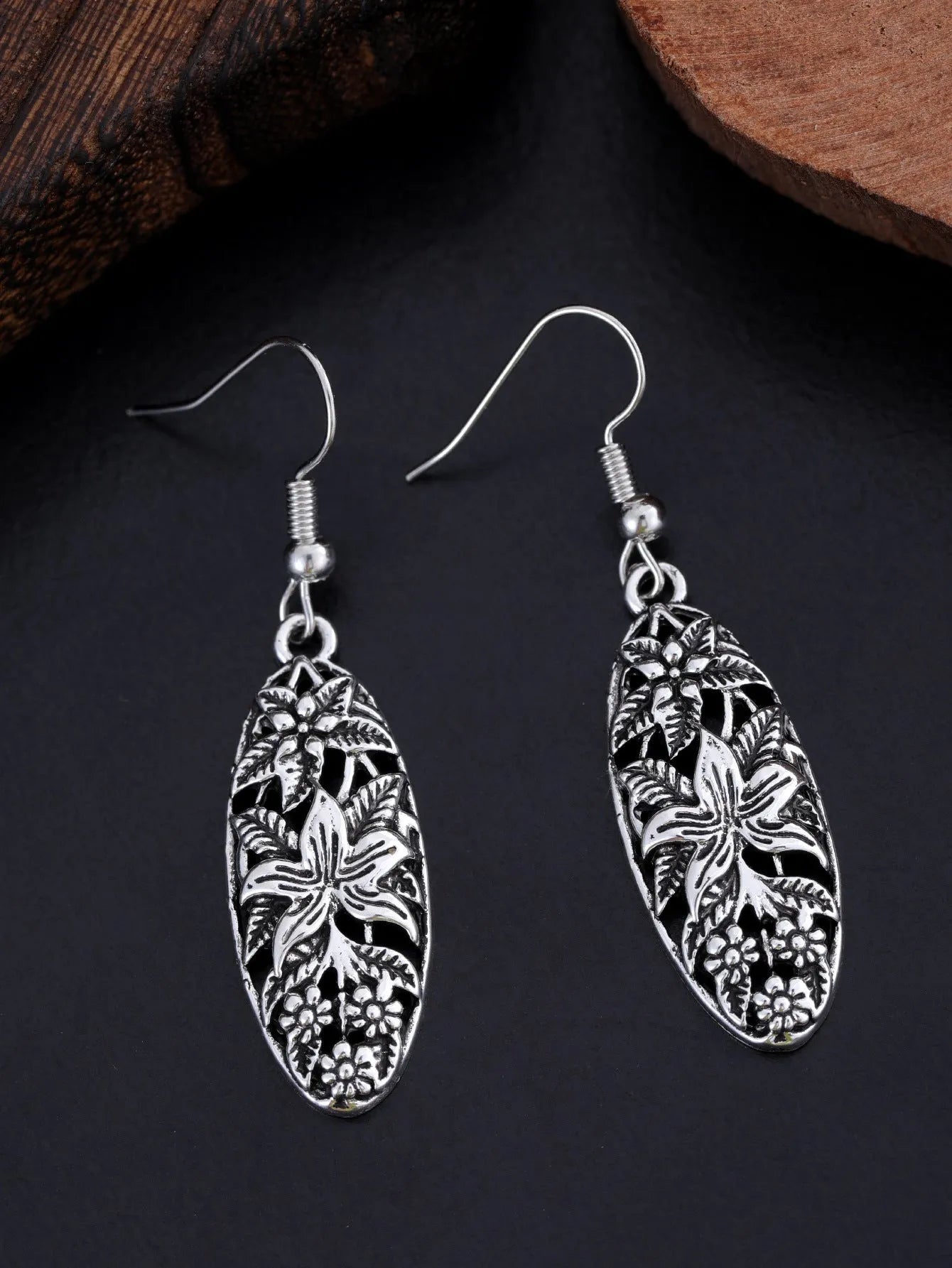 Pair of silver-tone retro hollowed out long water droplet drop earrings on light background