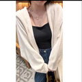 A woman wearing a long, loose, hooded beige knitted cardigan in a Korean casual style.
