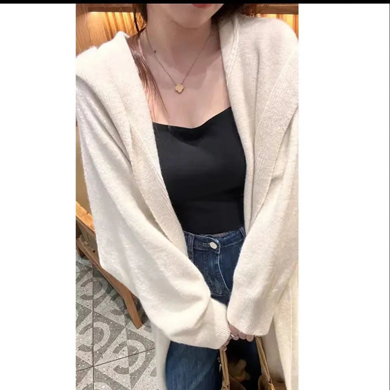 A woman wearing a long, loose, hooded beige knitted cardigan in a Korean casual style.