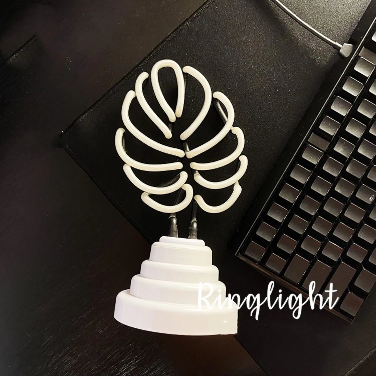 White tube bamboo shape desktop lamp emitting green light, with USB cable.