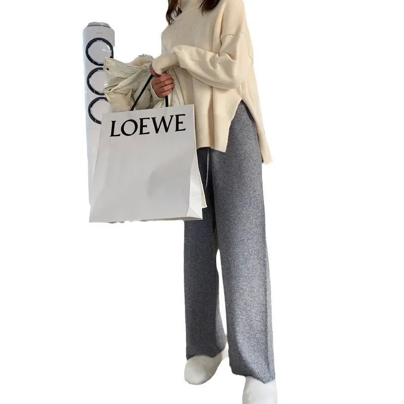 Woman wearing cream white high-waisted knitted wide-leg pants with a drooping mopping silhouette.