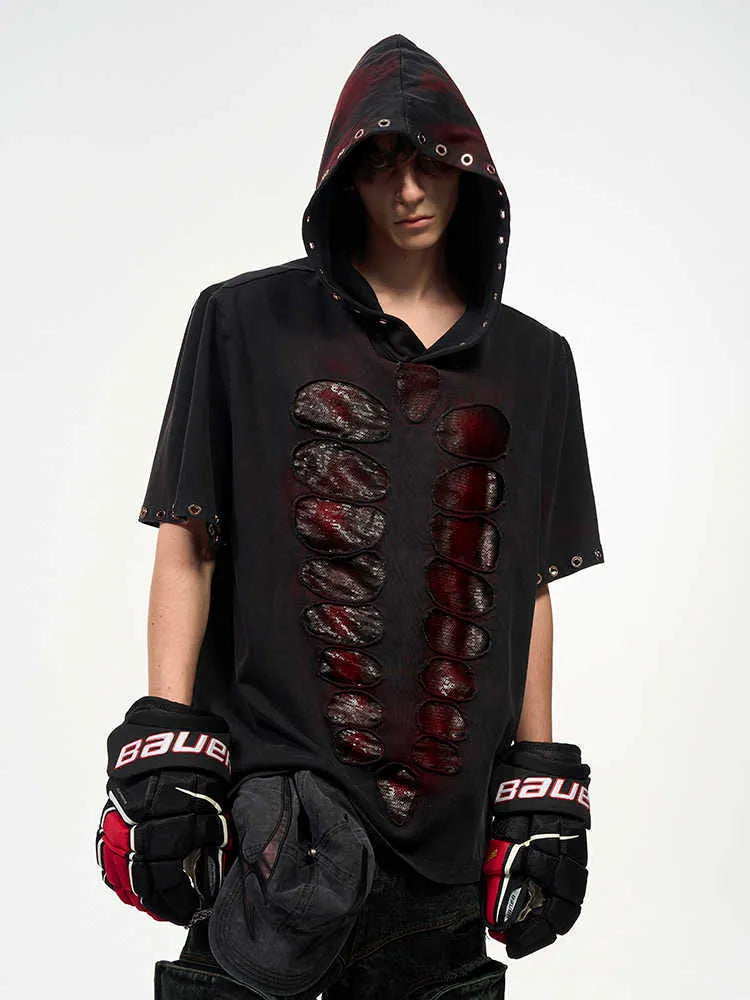Black loose-fit men's hooded T-shirt covered in reflective sequins, shown in a casual setting.