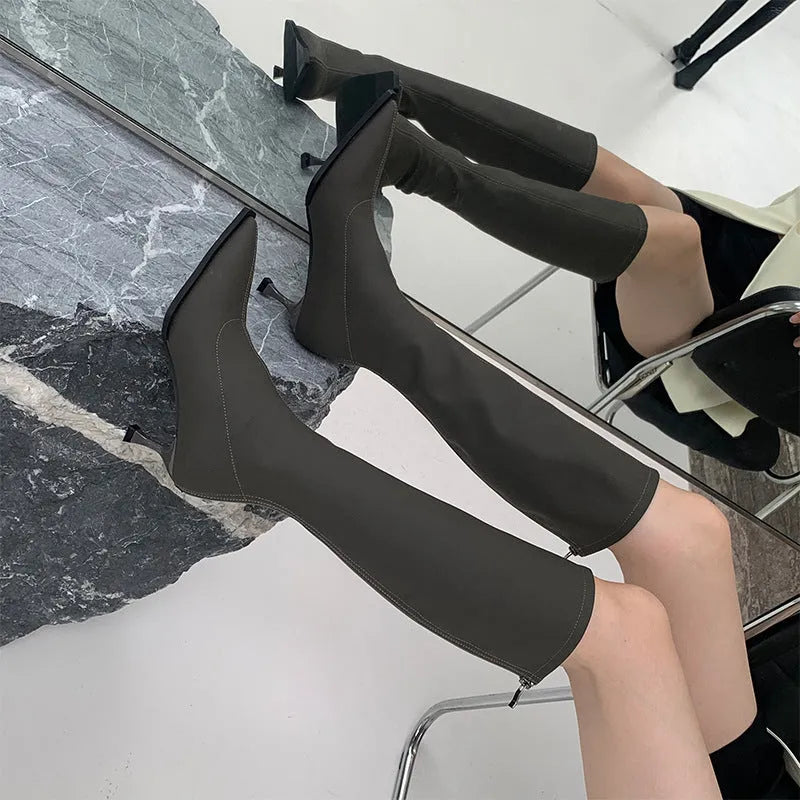 Black pointed toe women's below-the-knee stiletto boots with a back zipper on a white background