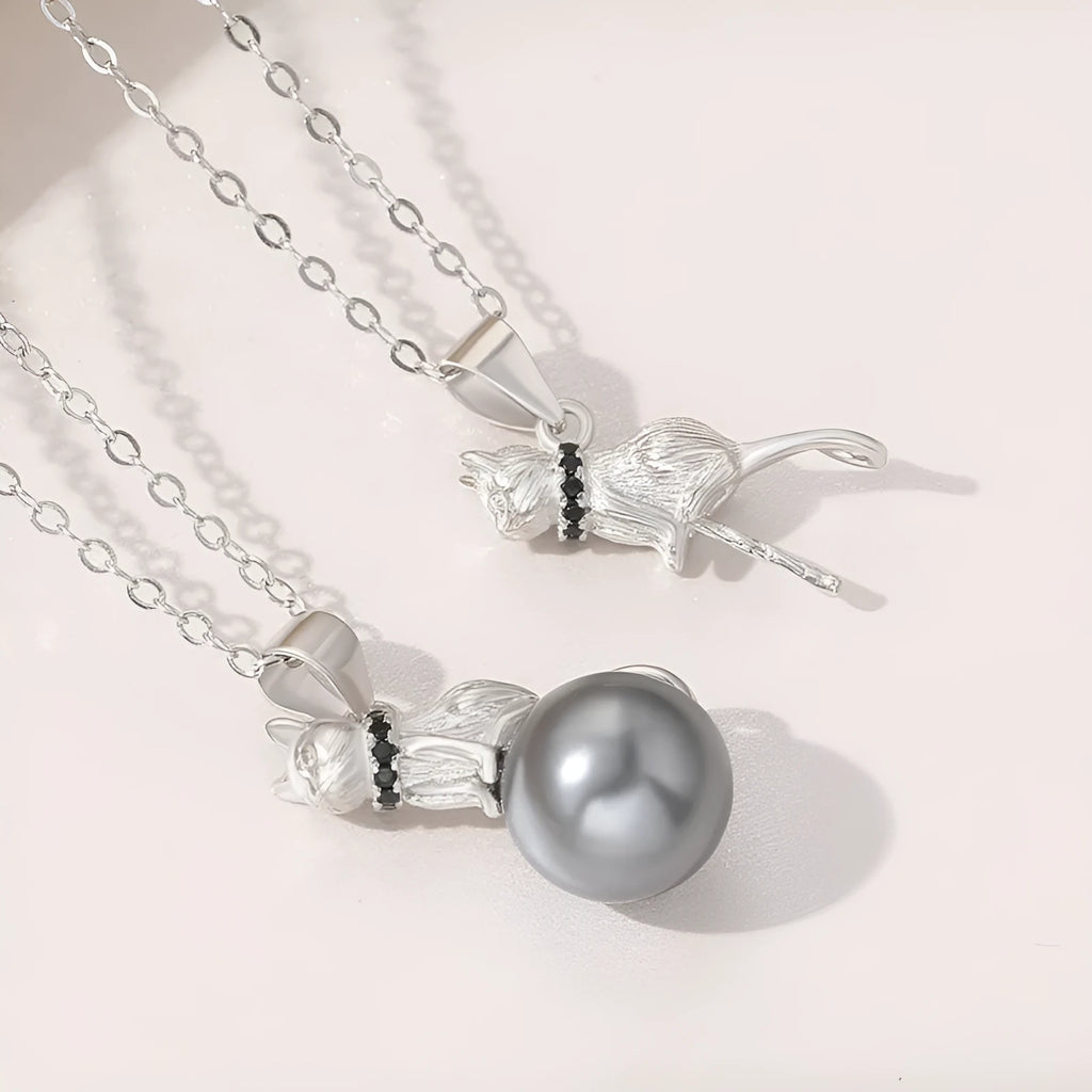 Close-up of a sterling silver cat pendant necklace on a dark background, showing the detailed charm.