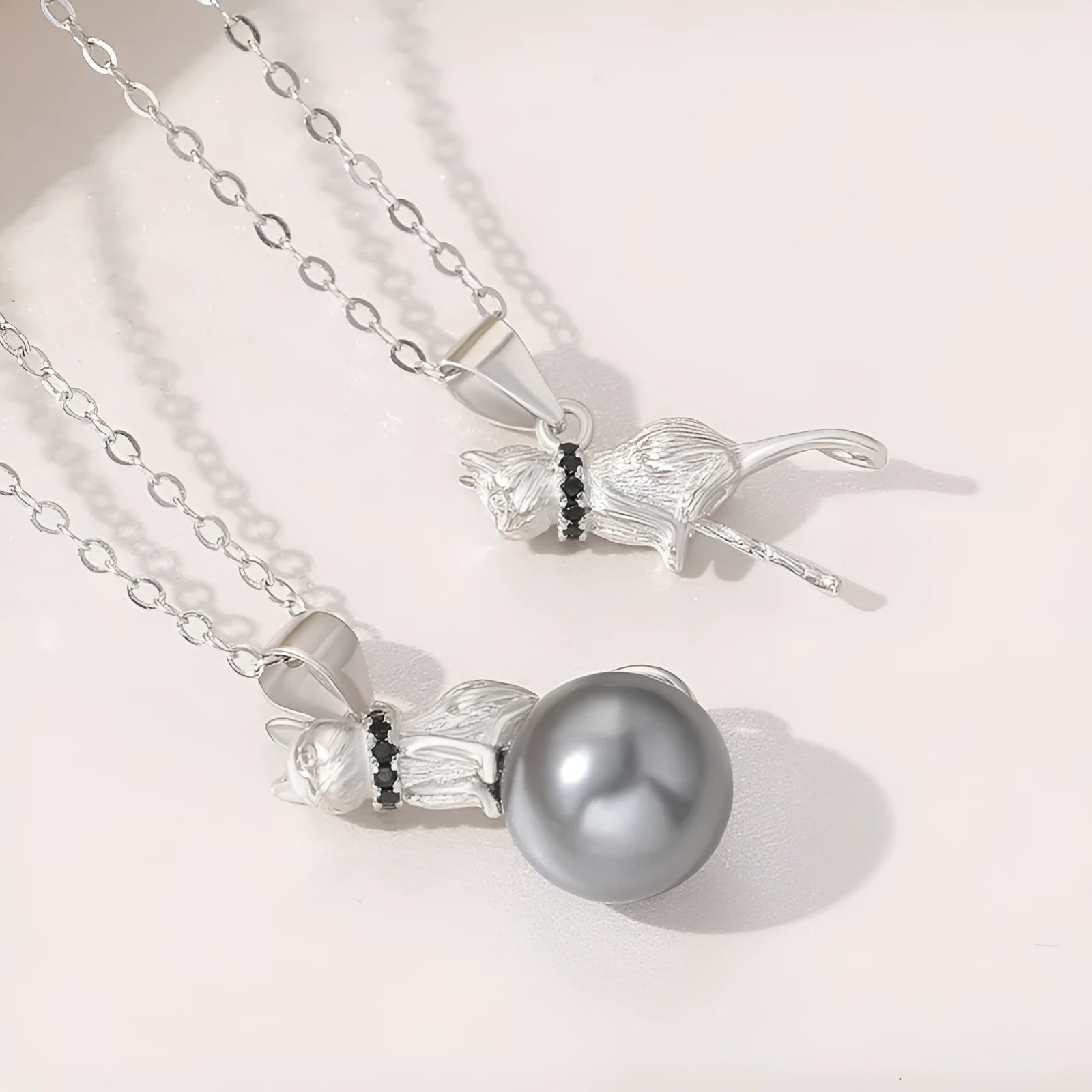 Close-up of a sterling silver cat pendant necklace on a dark background, showing the detailed charm.