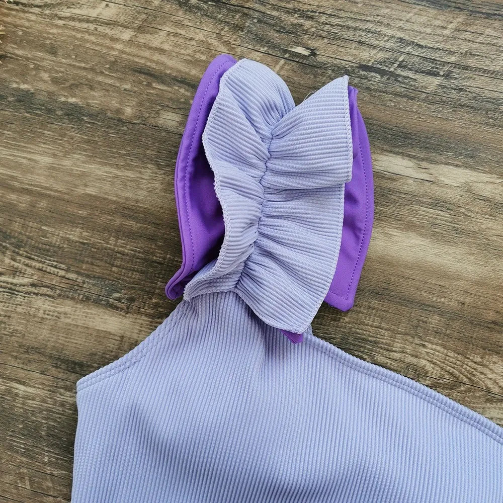 Women's single-shoulder one-piece swimsuit with a suspender strap in a solid colour.