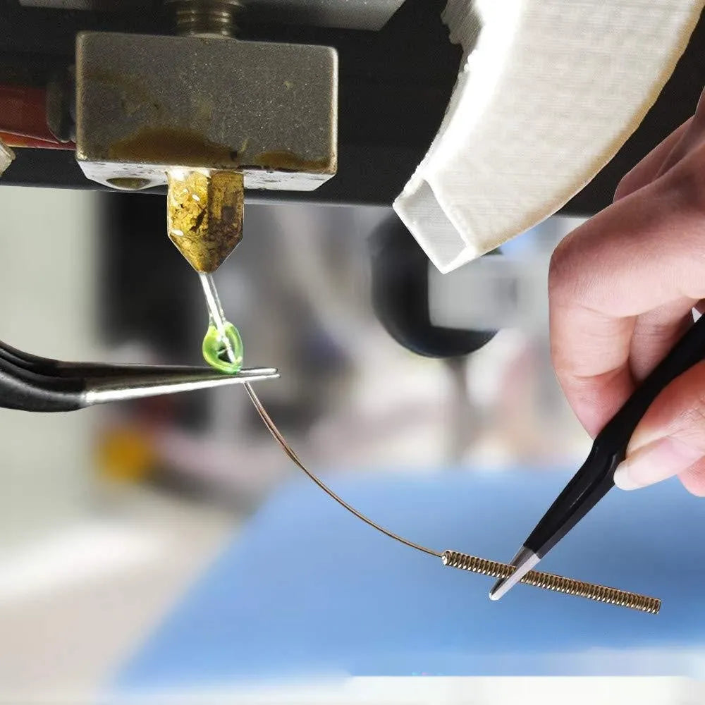 Brass MK8 3D printer nozzle and a pointed stainless steel cleaning pin on a grey background.