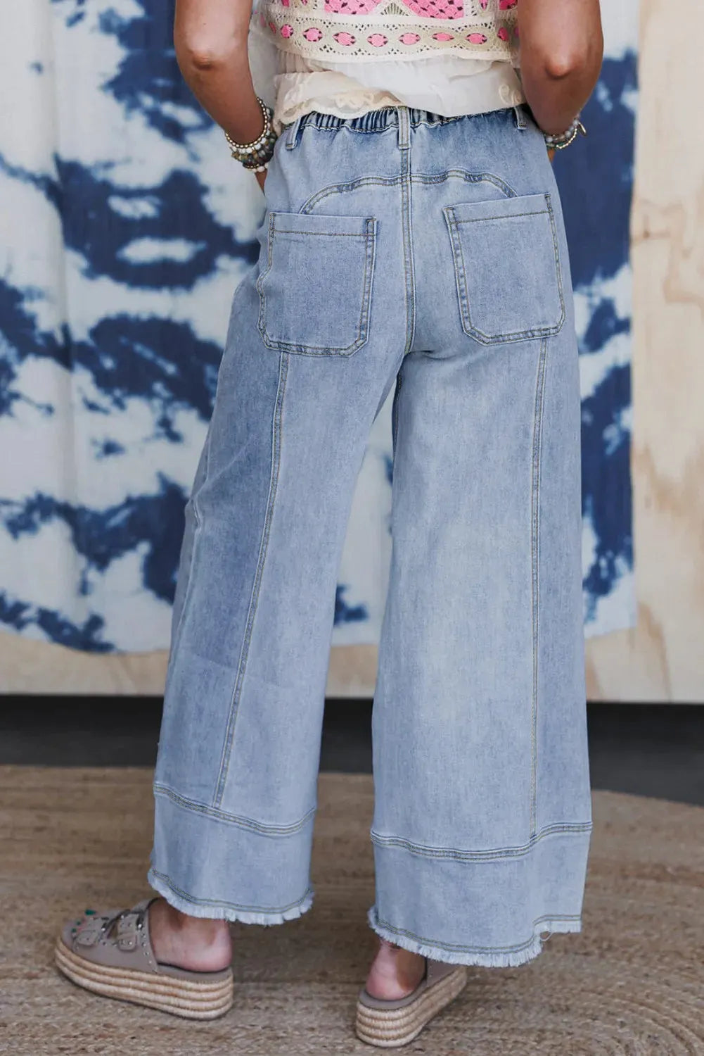Beau Blue wide leg denim trousers on a hanger, showing drawstring waist, seam detailing, and raw hem.