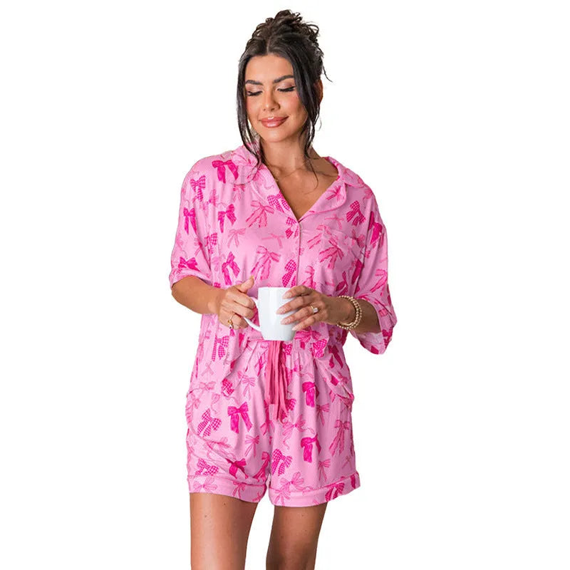 Pink women's bow print polyester two-piece pajama set on a hanger
