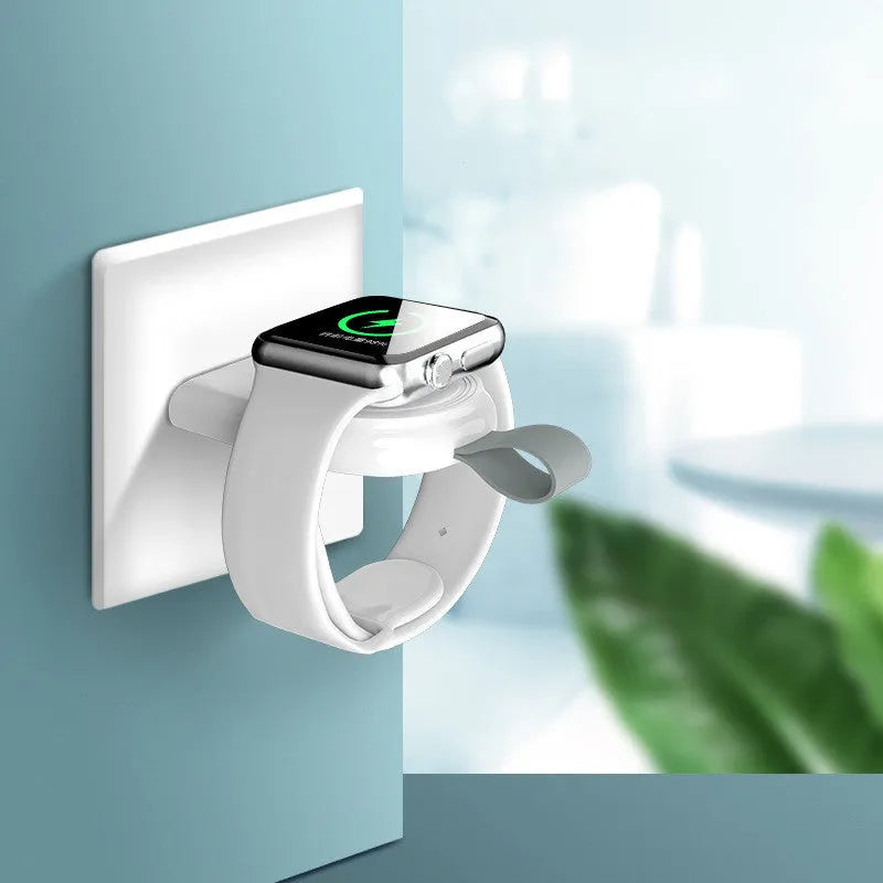 Portable Apple Watch wireless charging dock in white on a wooden table, with USB cable attached.