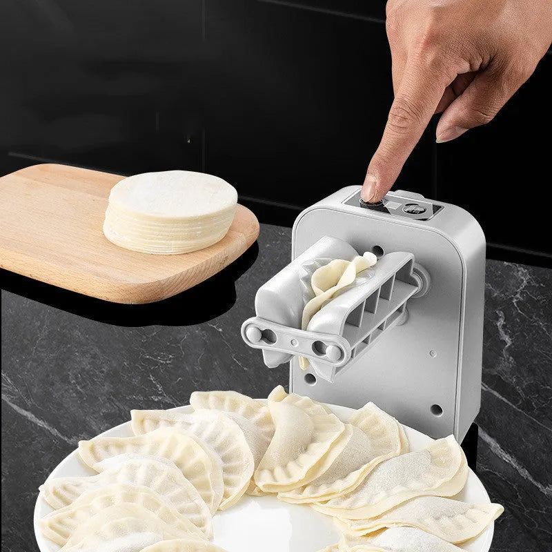 White automatic electric dumpling maker machine on a kitchen counter with USB cable and accessories