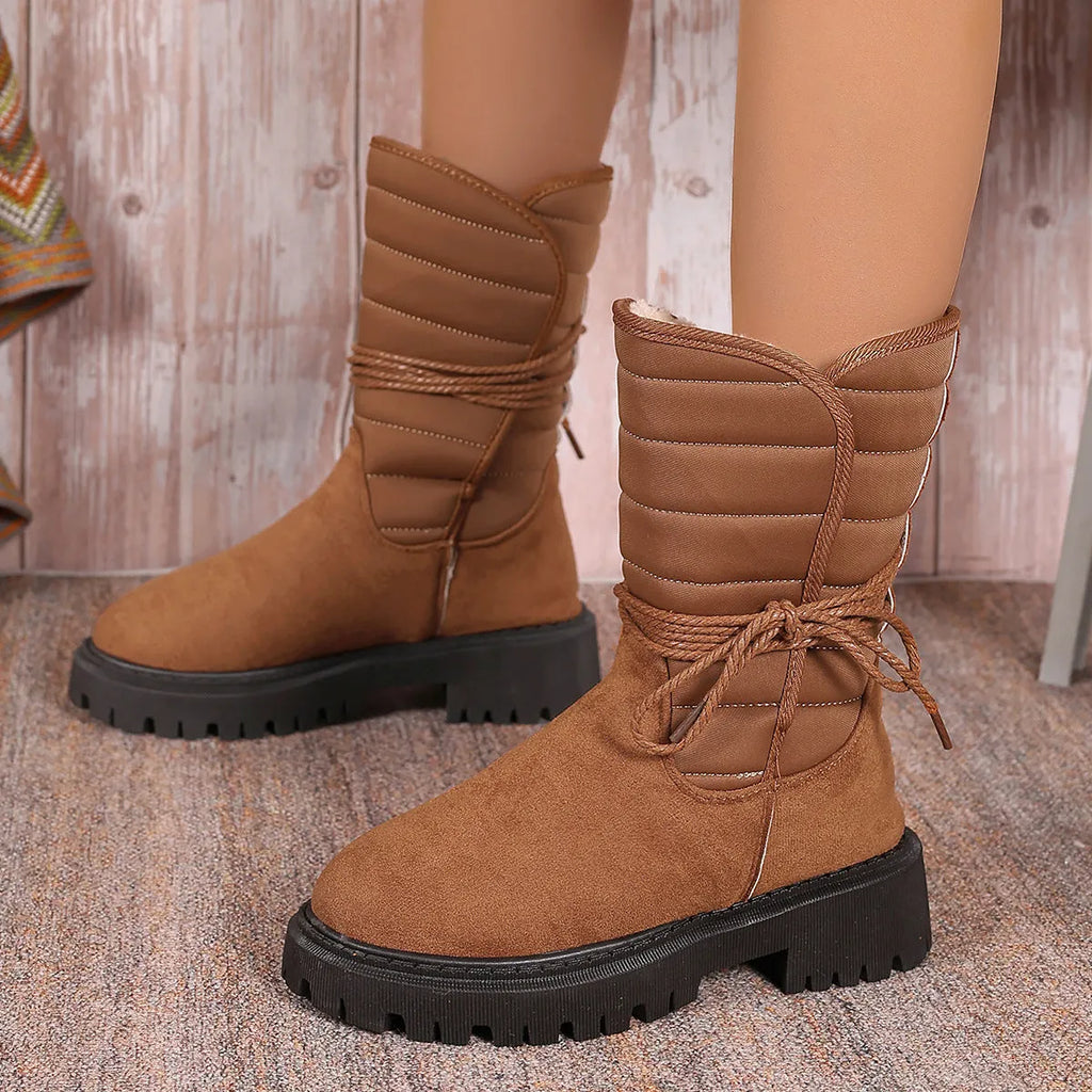 Women's black chunky heel snow boot with lace-up design and suede upper on a white background.