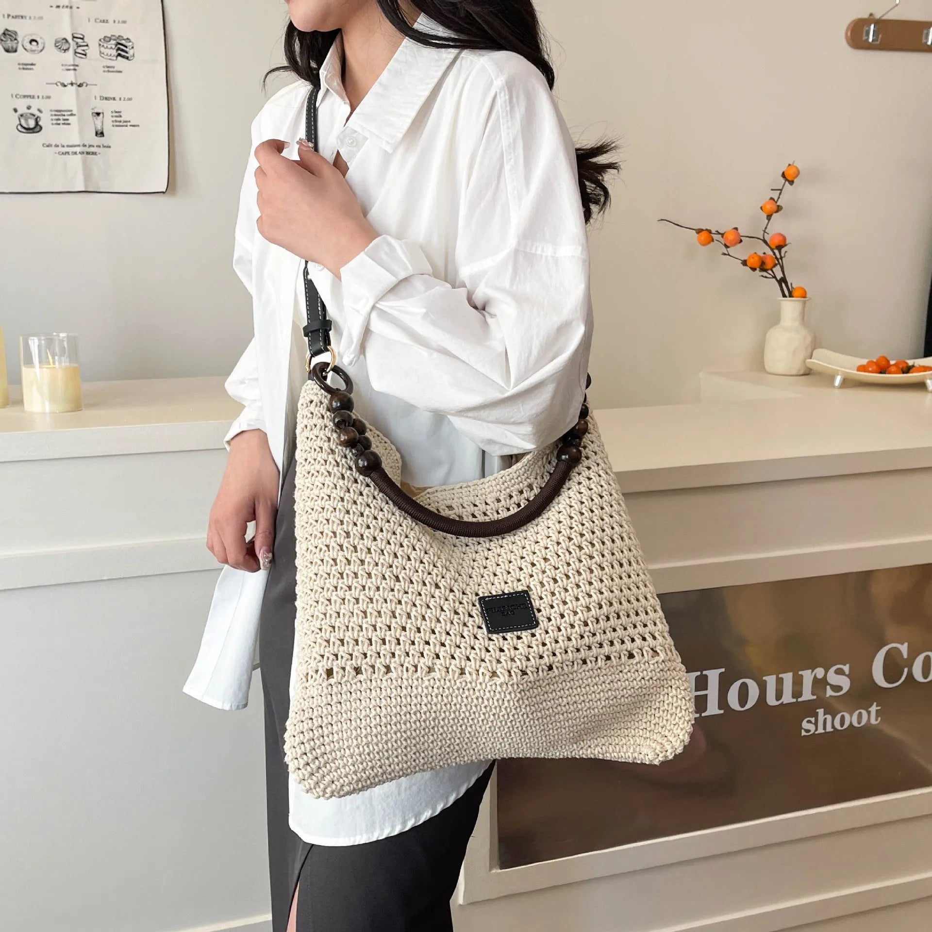 Knitted large capacity tote beach bag in bucket shape with contrast stitching and crossbody strap, black colour, on a plain background
