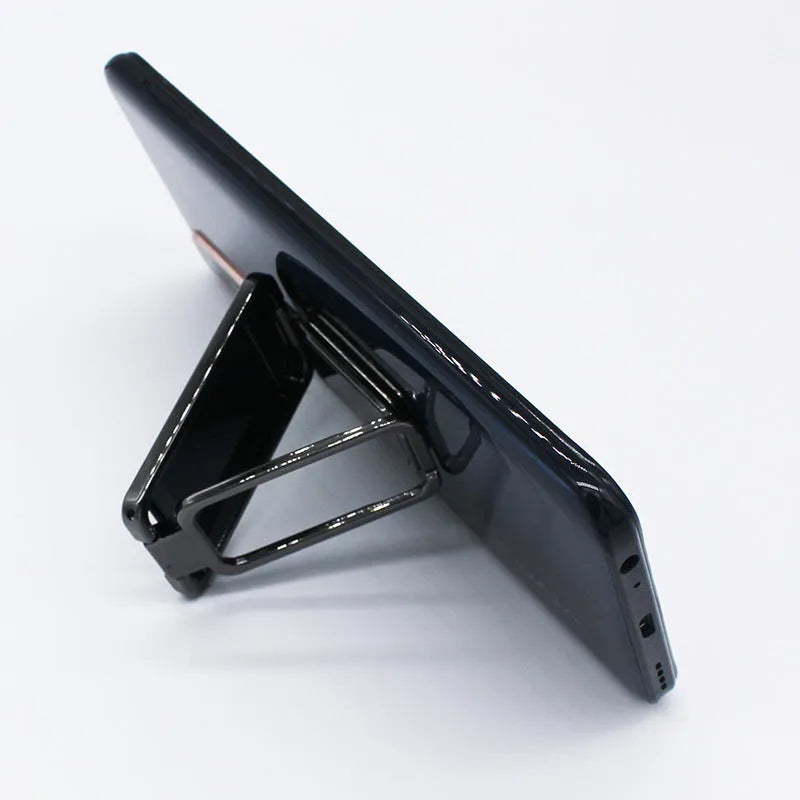 Foldable zinc alloy phone holder ring buckle in silver on a desk propping an iPhone at an angle.