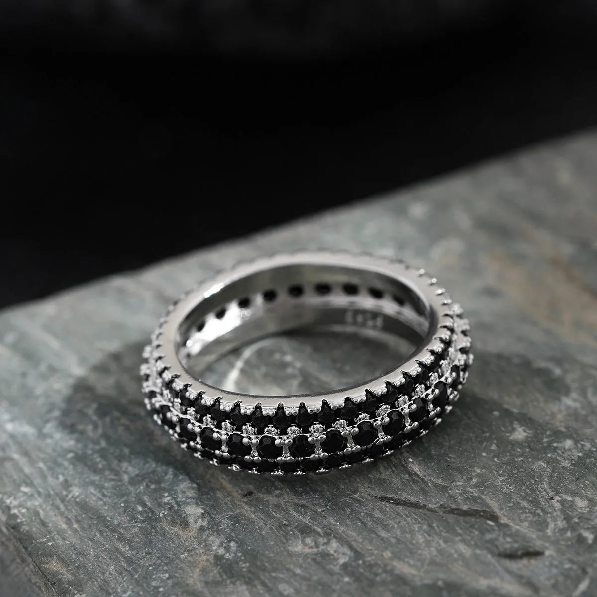 Geometric triangle personalised zircon ring in yellow gold on a grey background.