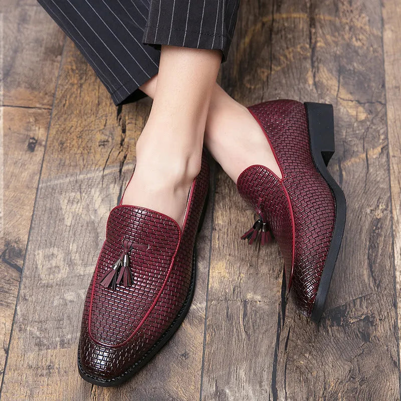 Men's black pointed toe slip-on shoes with a decorative tassel on the front.