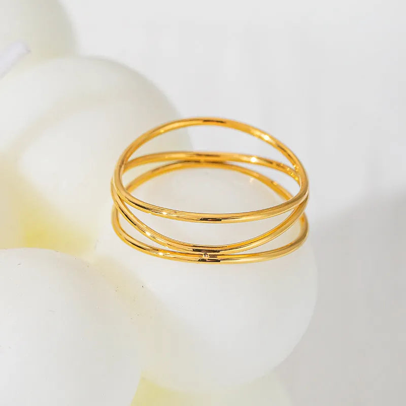 Gold geometric titanium steel ring with a three-layer coil design on a hand.