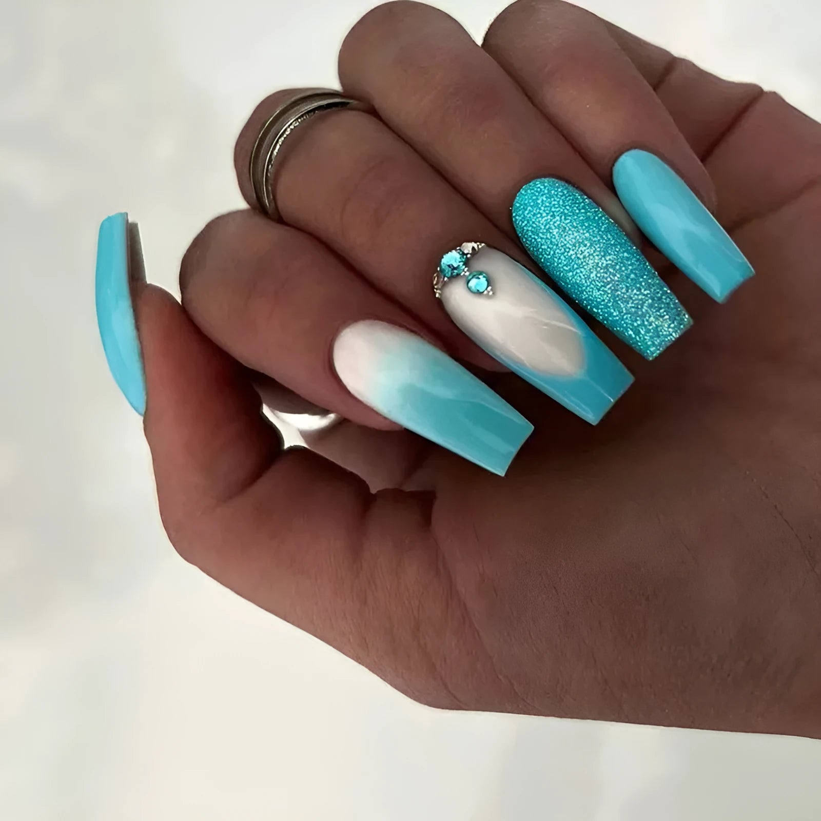 Long ballet-shaped press-on nail patches in solid smart blue diamond colour with glue bottle.