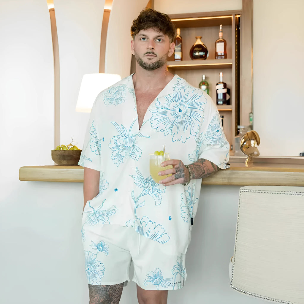 Man wearing a loose grey short-sleeve top with a floral print pattern