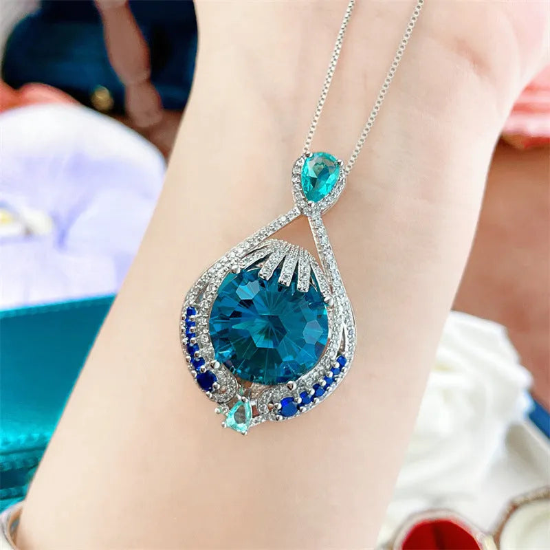 Close-up of a women's geometric necklace with a blue crystal pendant on a water wave chain.