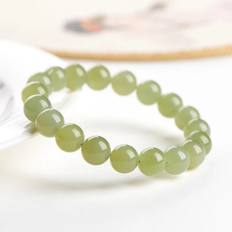 Polished Hetian jade bead bracelet in ice-clear colours on a wrist, showing spherical beads.
