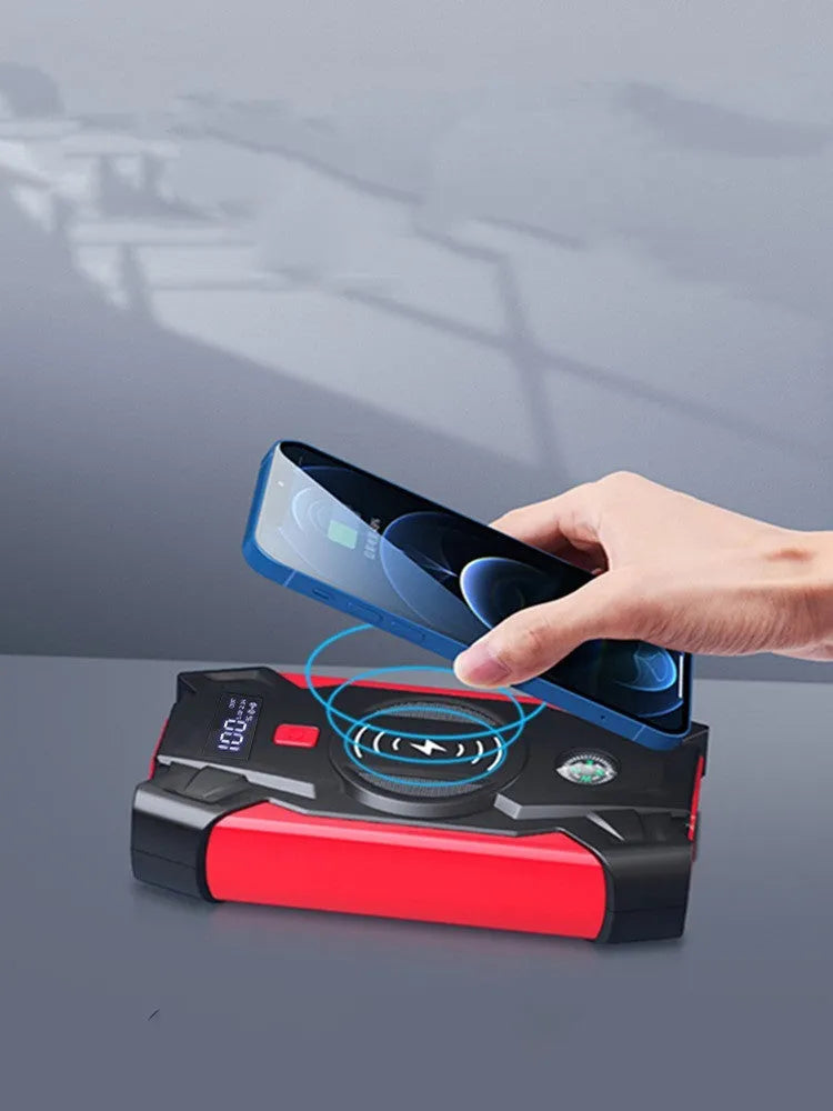 Compact red car battery jump starter unit with cables and clips on a dark background.