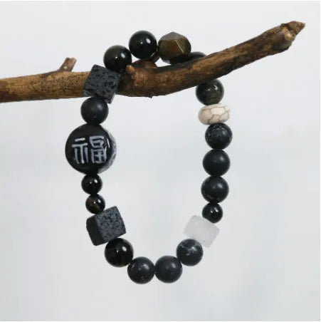Natural black agate and ceramic round bead hand-woven bracelet on plain background, unisex original design