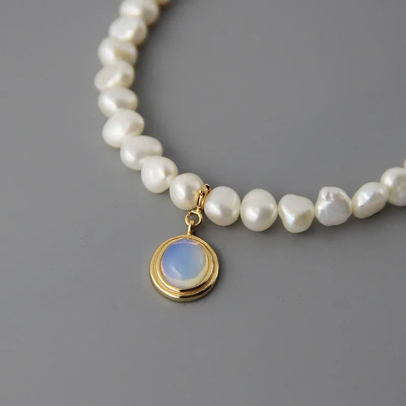 Silver geometric necklace with an irregular pearl pendant on an adjustable chain.