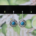 Handmade ethnic earrings with a Tibetan silver geometric flower disk design and turquoise stones.