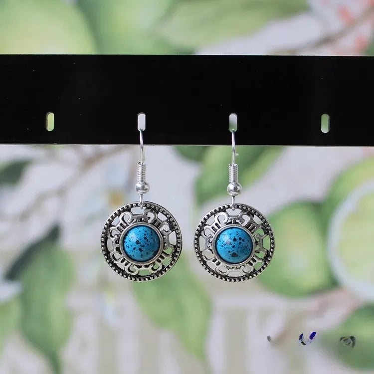 Handmade ethnic earrings with a Tibetan silver geometric flower disk design and turquoise stones.