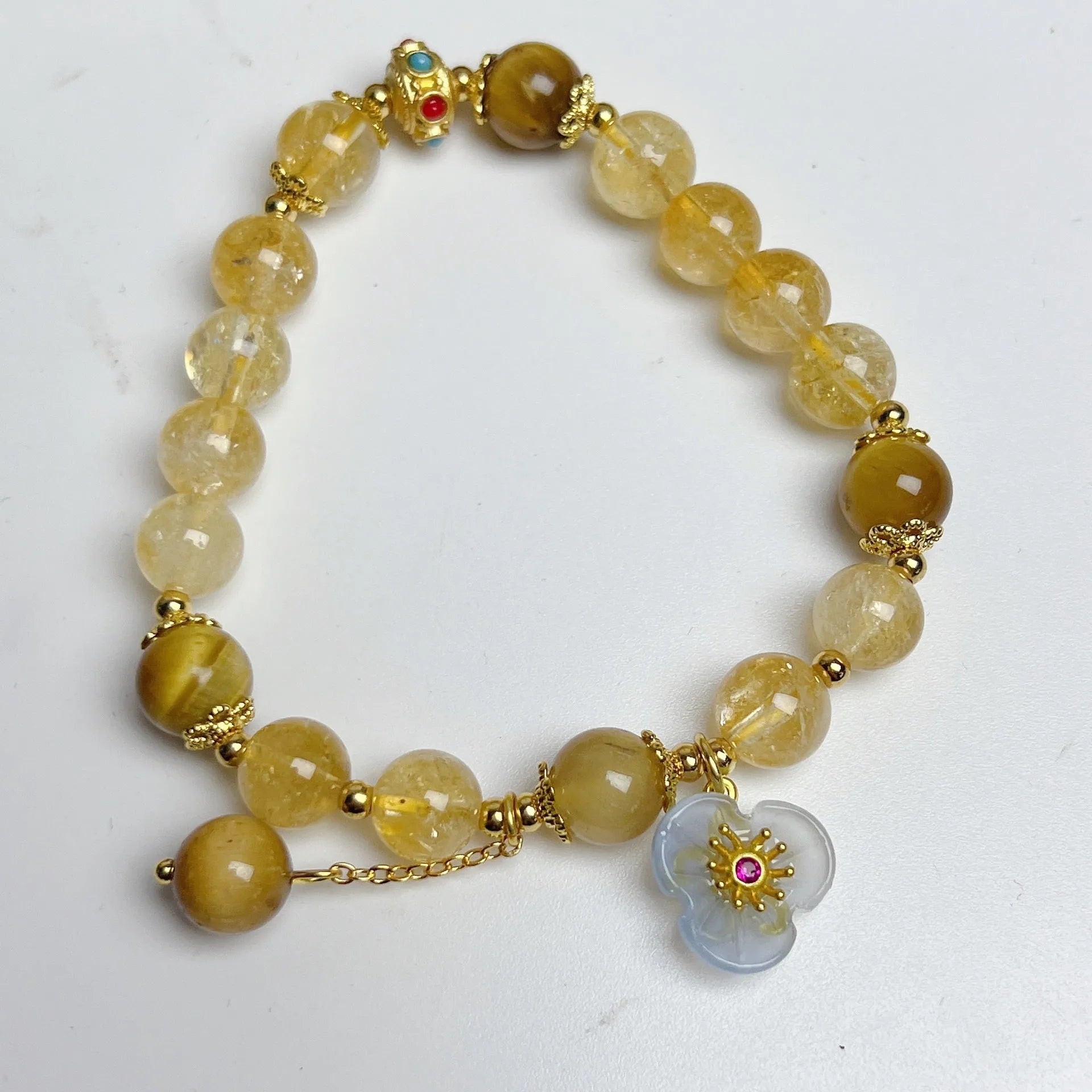 Women's handcrafted citrine crystal bracelet with flower tassel pendant on white background