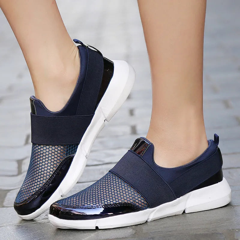 Blue low-top women's mesh sneakers with a casual design on a hard floor surface.