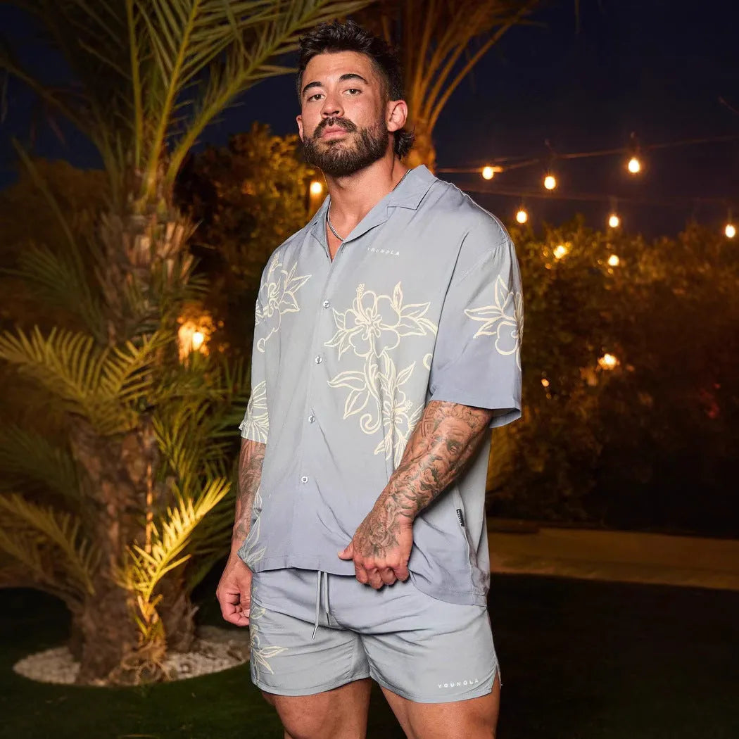 Man wearing a loose grey short-sleeve top with a floral print pattern