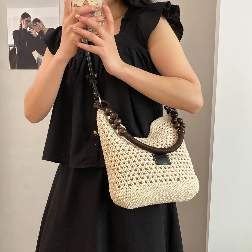 Knitted large capacity tote beach bag in bucket shape with contrast stitching and crossbody strap, black colour, on a plain background