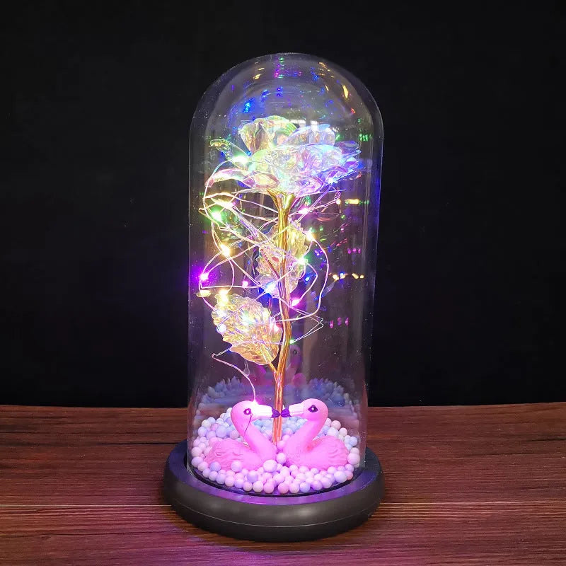 Artificial gold rose in glass flask with LED lights on black base, 20cm tall