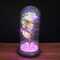 Artificial gold rose in glass flask with LED lights on black base, 20cm tall
