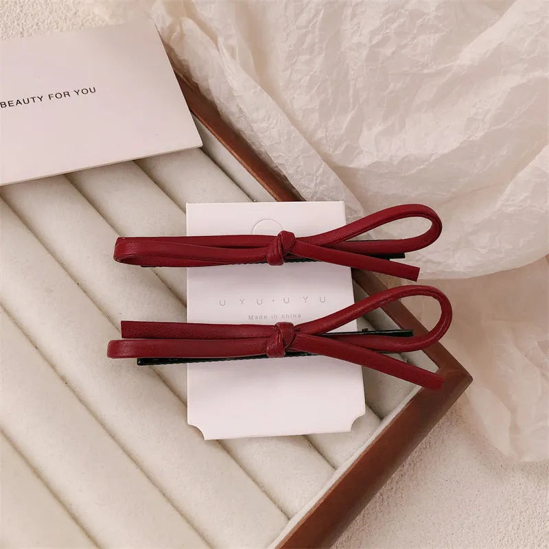 Wine red leather hair barrette with bow decoration shown from front and side views