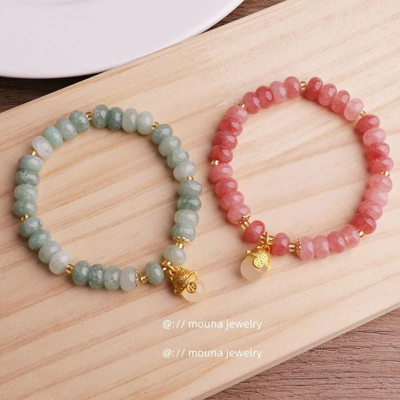 Women's handmade strawberry quartz Lucky Cat bracelet on a neutral background