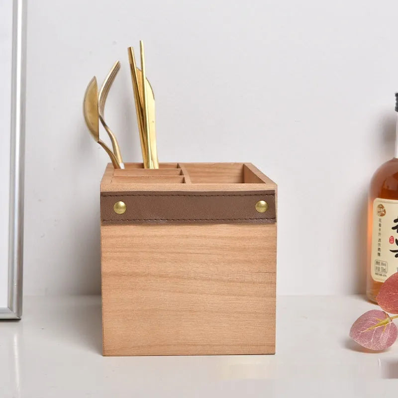 Open wooden kitchen storage box with internal grid holding knives, forks, and chopsticks.