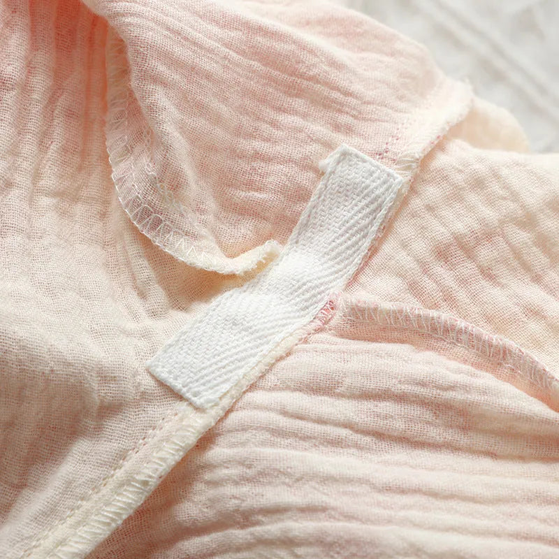 Women's pink cotton gauze lounge suit set with long sleeve top and trousers on a hanger.