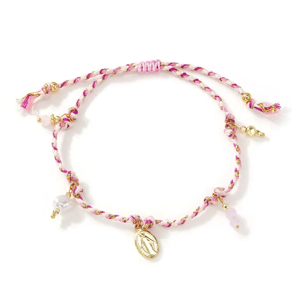 Close-up of a colourful hand-woven braided rope bracelet with a carrying strap tag on a woman's wrist.