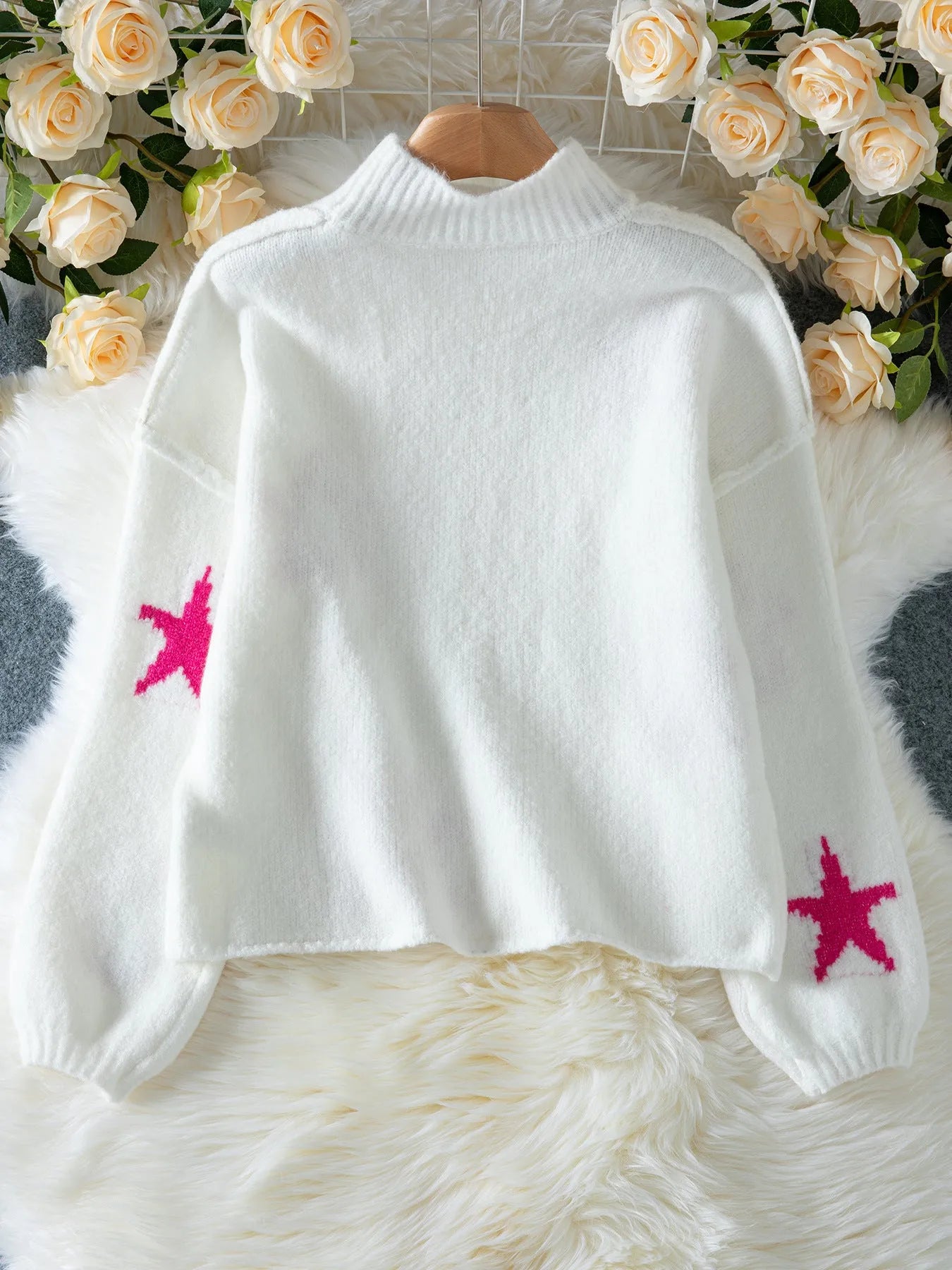 Women's white loose turtleneck pullover sweater with a black five-pointed star pattern on the front.