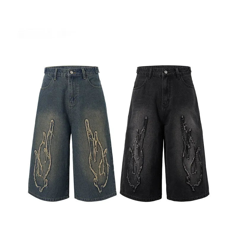 Men's black denim shorts with cropped flame embroidery patch on leg, straight cut.