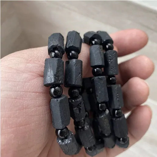 Natural black tourmaline rough stone bracelet unisex 10mm bead size on plain background