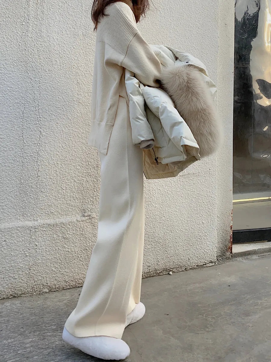 Woman wearing cream white high-waisted knitted wide-leg pants with a drooping mopping silhouette.