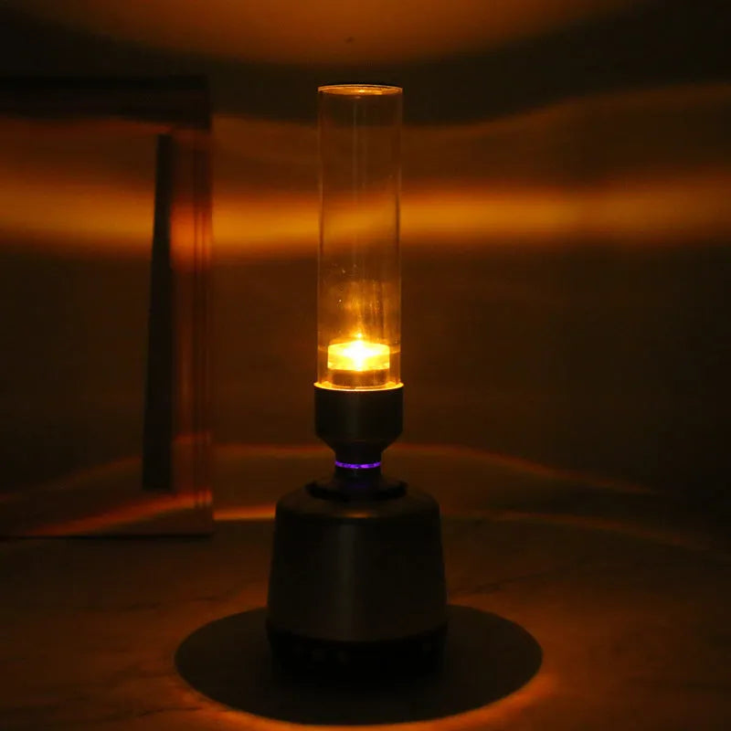 White silver Bluetooth speaker with integrated candlelight atmosphere night light on a table.