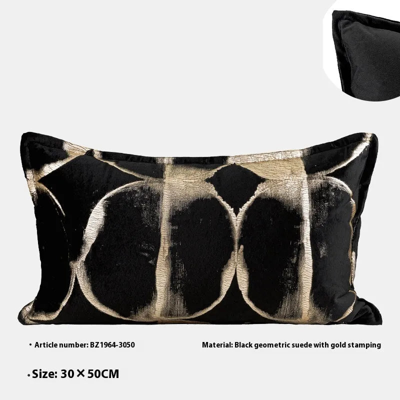 Black and gold abstract patterned decorative flannel cushion on a grey sofa.