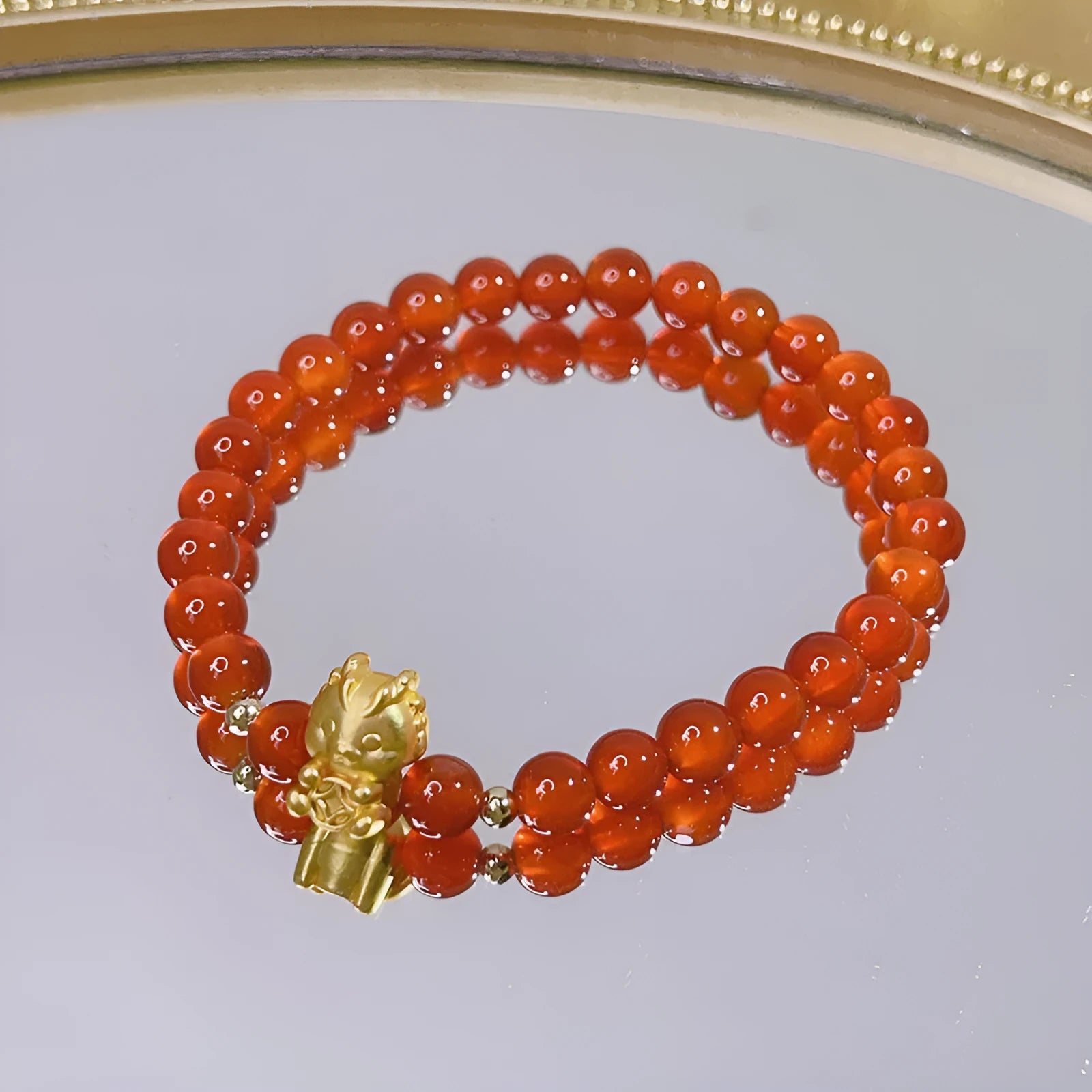 Handmade red agate bracelet with dragon motif and lucky charm beads.