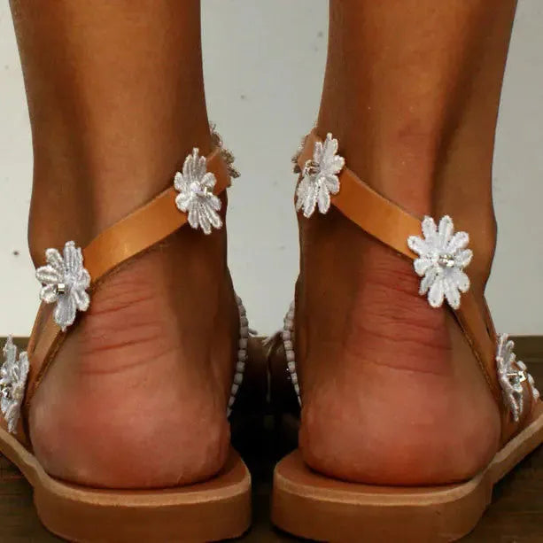 Brown women's beach sandals with floral pattern, flat rubber sole, and herringbone toe design